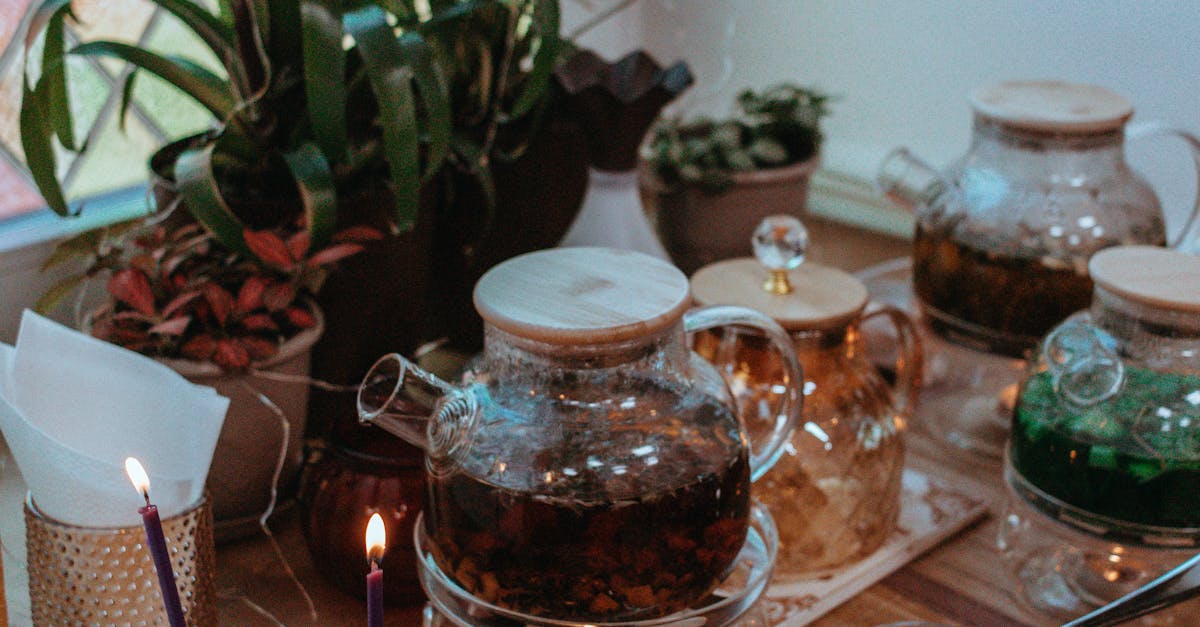 Warm indoor scene with brewed herbal teapots, plants, and candles on a wooden table.