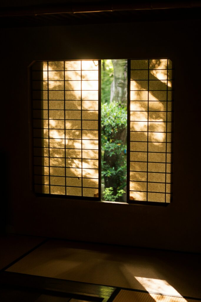 Tranquil scene of Japanese interior design featuring a Shoji screen window overlooking a lush garden.