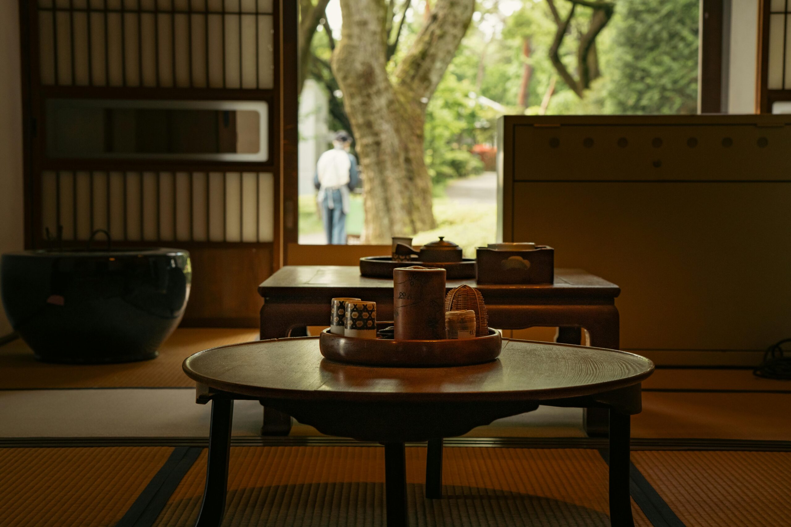 Japanese tea room interior with view of garden and person outside.