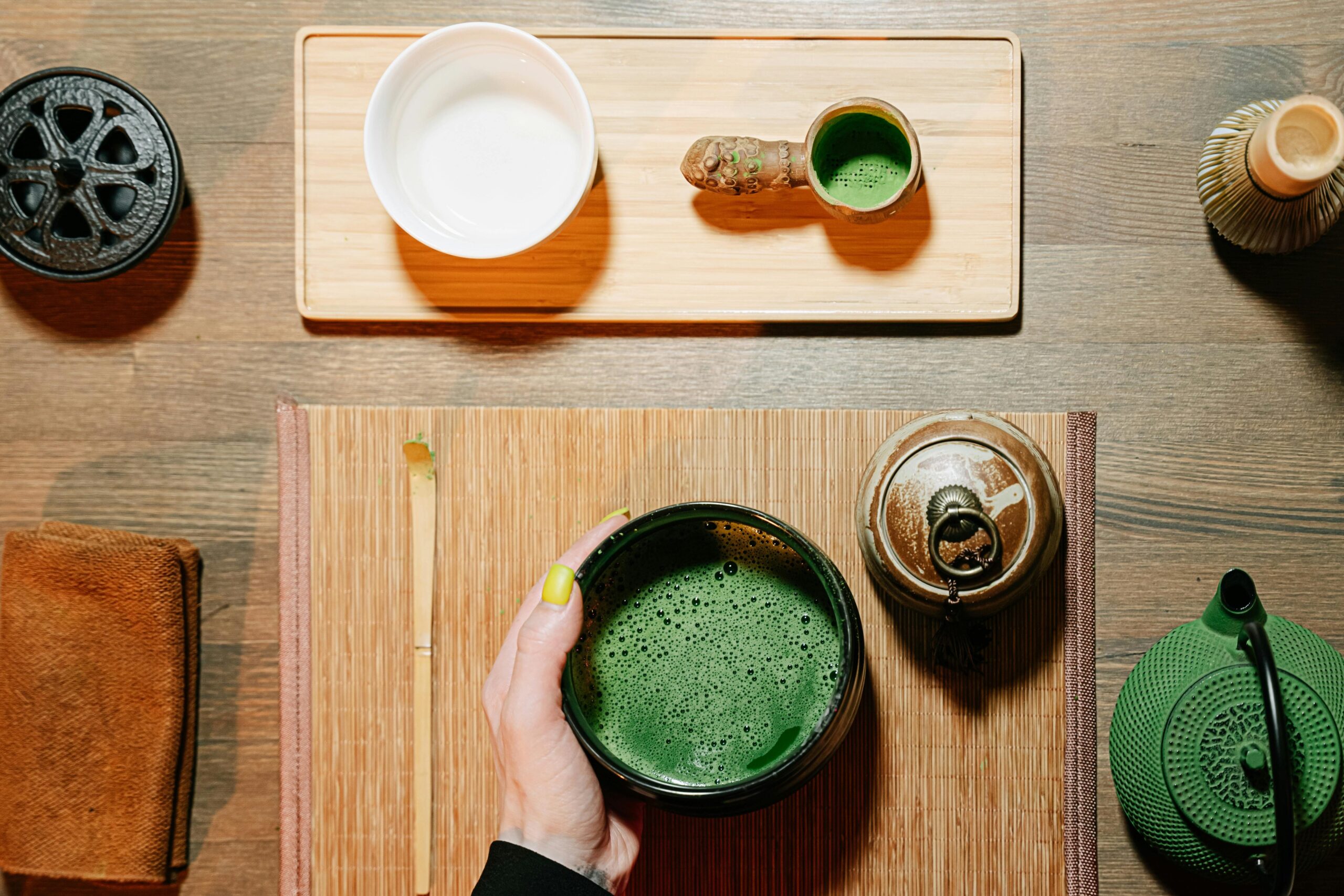 Overhead view of traditional matcha tea ceremony elements on a wooden table.